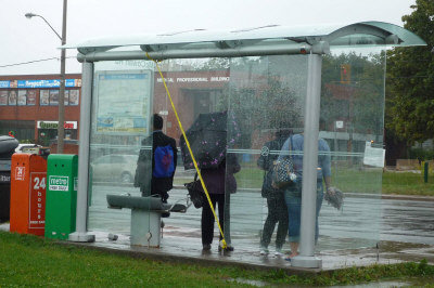 玻璃墙遭击碎，民众站在候车亭内，还是得撑着雨伞躲风躲雨等公车。 (记者葛健生/摄影)</p></p> <p><p>