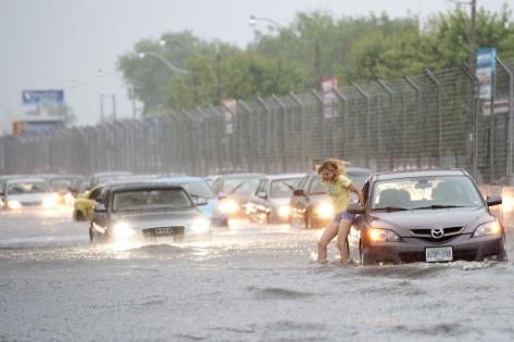 A woman gets gets out of her car to check it in flood water on Lakeshore West during a storm in Toronto on Monday, July 8, 2013. THE CANADIAN PRESS/Frank Gunn
