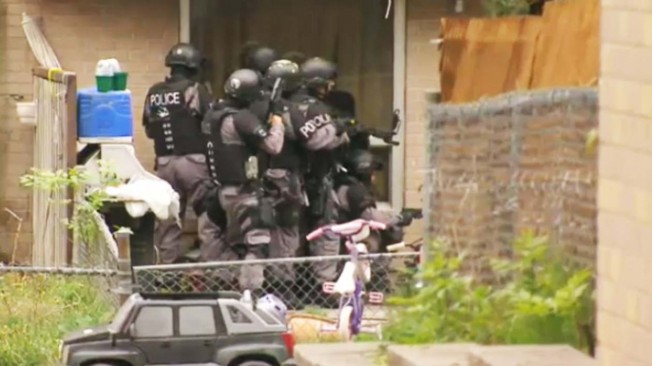 警方的紧急行动组成员，守在一间镇屋门外，准备逮捕三名嫌犯。 （图：CTV）