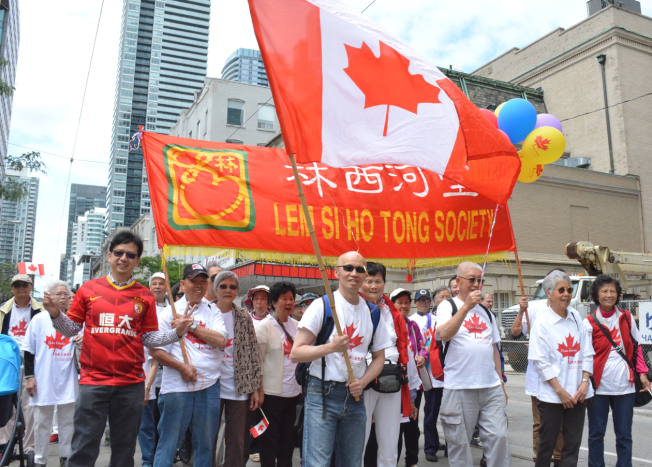 林西河堂队伍高举国旗参加游行。 （记者谢君/摄影）