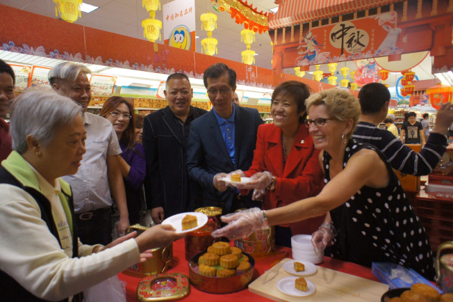 韦恩(右一)向华人分送月饼。陈国治(右三)参加活动。(记者沈丹心／摄影)