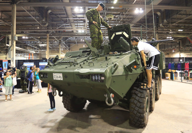 在展览会上的国防教育展区参观装甲车。（取材自新华社）