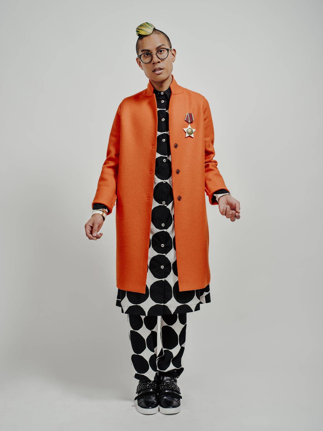 Kassam wears a coat by Harris Wharf of London over a shirt and trousers by Marimekko. His eyeglasses are Céline, his sneakers are Michael Kors, and his Bulgarian medal is a vintage heirloom.