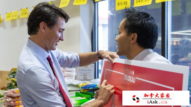 Justin Trudeau signe la pancarte électorale qu'un homme tient dans ses mains.